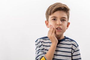 child holding side of face with dental pain